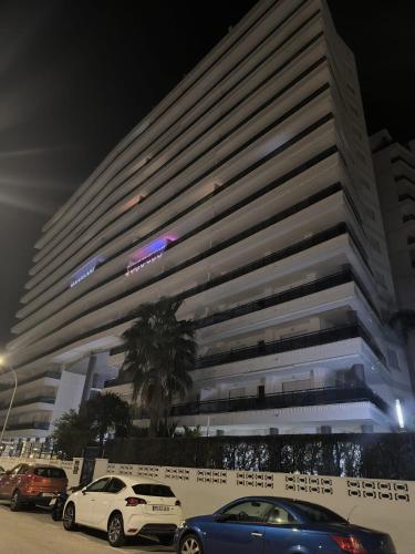 a large building with cars parked in front of it at Apartamento El Eden in Playa de Gandia