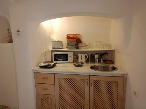 a small kitchen with a sink and a microwave at Aegea Cave Houses in Mesaria