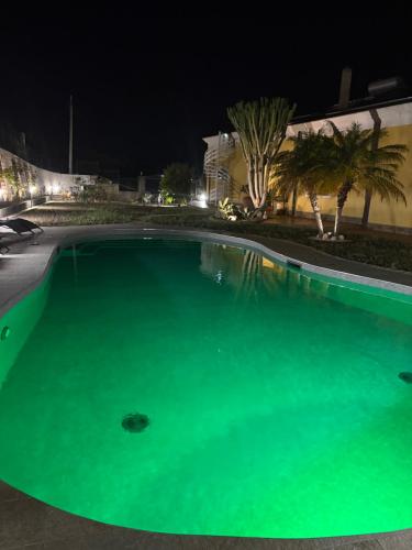 a large swimming pool with green water at night at Villa Gabry in Capo dʼOrlando