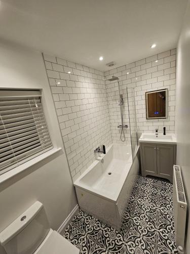 a bathroom with a tub and a toilet and a sink at Modernised 3 Bed House in Wrexham