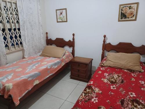 a bedroom with two twin beds and a night stand at CASA 3 MIN a PÉ da PRAIA DO FORTE - CHURRASQUEIRA - WI FI in Cabo Frio