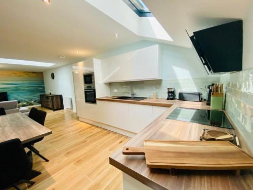 une cuisine avec des armoires blanches et une table en bois dans l'établissement Les gîtes du pécheur !, au Crotoy