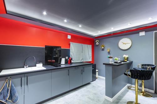 eine Küche mit roten Wänden und einer Uhr an der Wand in der Unterkunft Secret Night Pamiers in Pamiers