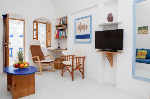 a living room with a tv and a table and chairs at Aegea Cave Houses in Mesaria
