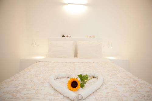 a bed with a sunflower in a heart shaped towel at Aegea Cave Houses in Mesaria