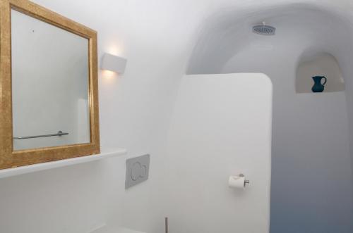 a mirror on a wall next to a bathroom at Aegea Cave Houses in Mesaria