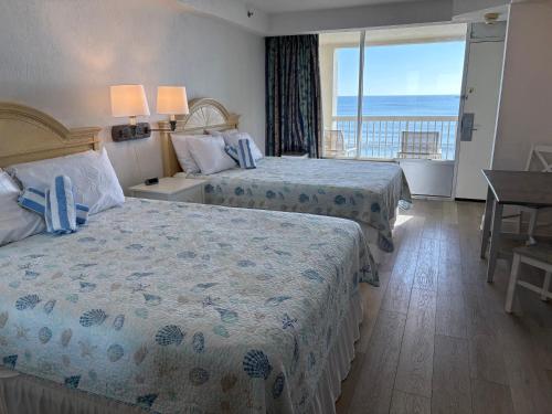 a hotel room with two beds and a balcony at Cozy Studio with Direct Ocean View in Daytona Beach