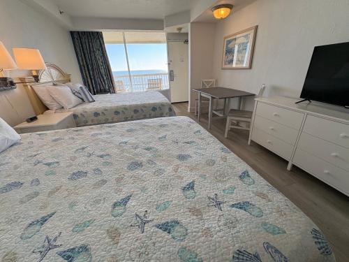 a hotel room with two beds and a television at Cozy Ocean View Studio, pools are not open in Daytona Beach