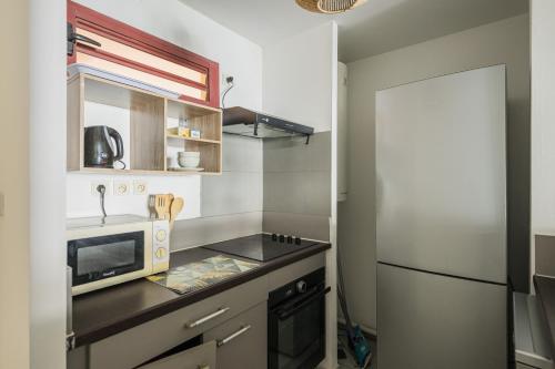 a small kitchen with a microwave and a refrigerator at La Ti Tonnelle - Centre et Confort - Wiskeys in Saint-Denis