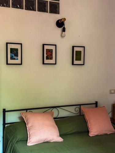 a bedroom with a green bed with four pictures on the wall at Casa Petra in Itri