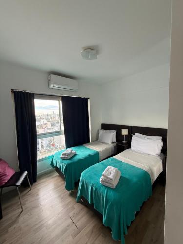 twee bedden in een kamer met een raam bij Apart Metropolitan in Buenos Aires