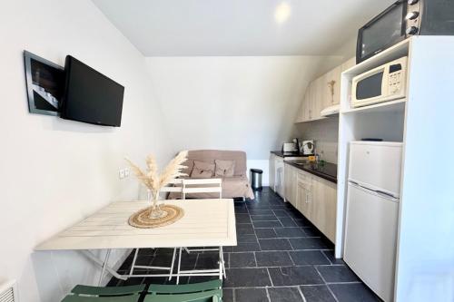 une petite cuisine avec une table et un réfrigérateur dans l'établissement Maisonnette tout confort - Vue mer - Piscine, à Guidel