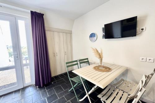une salle à manger avec une table et des chaises et une télévision dans l'établissement Maisonnette tout confort - Vue mer - Piscine, à Guidel