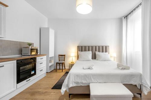 a white bedroom with a large bed and a kitchen at Medulic in Šibenik