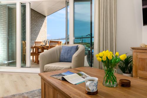 a living room with a table with a vase of flowers at Luxury Apartment very close to Tolcarne Beach in Newquay