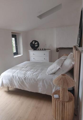 - une chambre avec un lit avec des draps blancs et une table dans l'établissement Maison Ile de Groix & sa voiture, à Groix