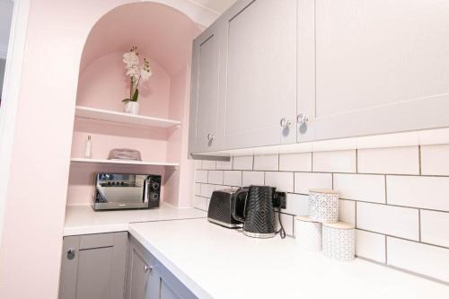 a kitchen with white cabinets and a toaster oven at 3 bed Modern Home, Vibrant & Stylish, Sleep upto 7 in Portsmouth