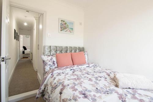 a white bedroom with a bed with pink pillows at 3 bed Modern Home, Vibrant & Stylish, Sleep upto 7 in Portsmouth