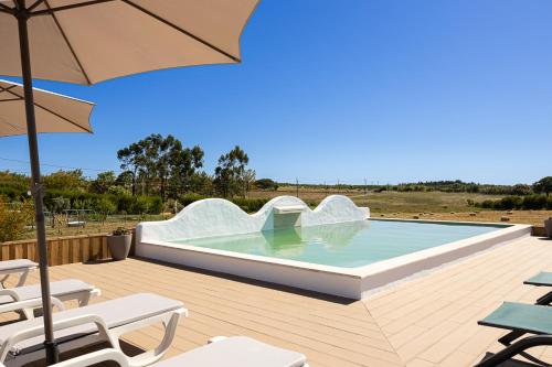 a pool with an umbrella and chairs on a deck at Craveira Country House in Sonega