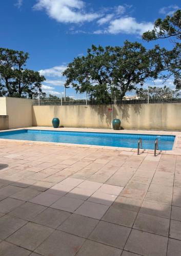 une piscine avec un mur et des arbres en arrière-plan dans l'établissement La casa des tortues, au Cap d'Agde