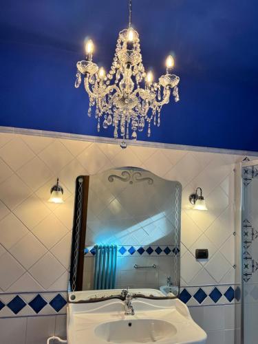a bathroom with a chandelier and a sink with a mirror at Agriturismo Colle Donatucci in Castagneto Carducci