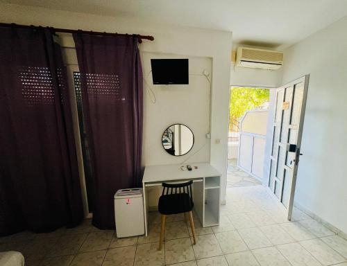 bagno con tavolo da trucco, specchio e sedia di PELEKAN rooms and apartments athina 12 a Pefkohori