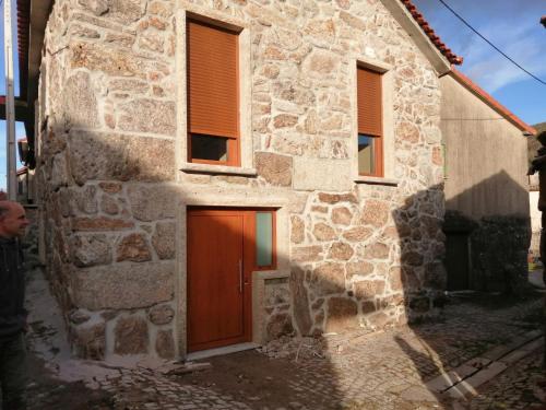 a stone house with a brown door and windows at Casa dos Avós in Fiães do Rio