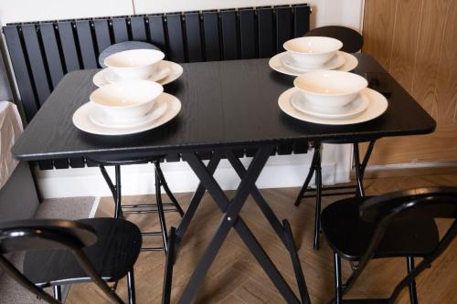 a black table with four cups and saucers on it at Brand New Studio Gem sleeps 3 in Thornton Heath