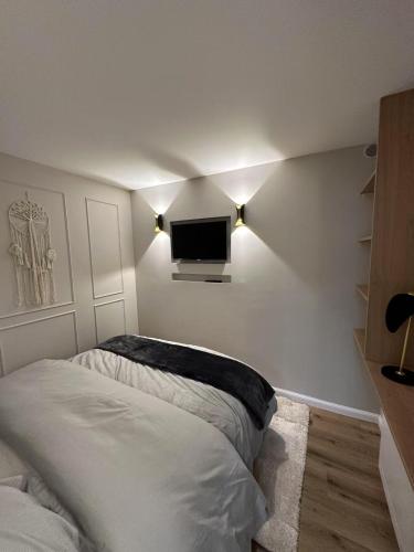 una camera da letto con un letto e una TV a parete di Getaway to Le Touquet - évasion au touquet a Le Touquet-Paris-Plage