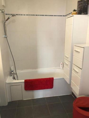 La salle de bains est pourvue d'une baignoire et d'une serviette rouge. dans l'établissement T3 St Jean de Luz, à Saint-Jean-de-Luz