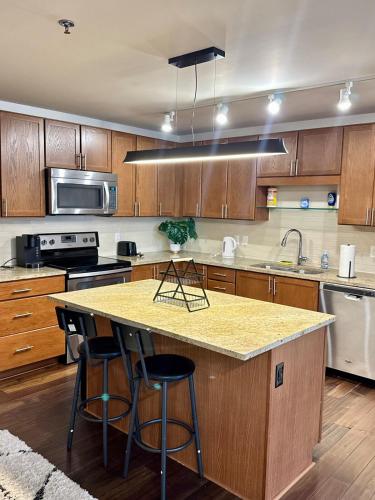 a kitchen with wooden cabinets and a island with bar stools at High-Rise Apartment in Downtown Dallas wPool in Dallas