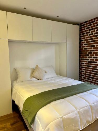 une chambre avec un grand lit blanc avec un mur de briques dans l'établissement Le Verrière Suite, à Paris