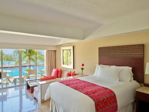 a hotel room with a large bed and a balcony at Grand Fiesta Americana Coral Beach Cancun - All Inclusive in Cancún