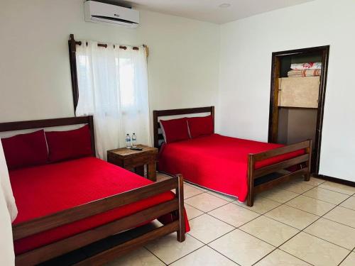 two beds in a room with red sheets at cabañas agua azul in Santa Cruz de Yojoa