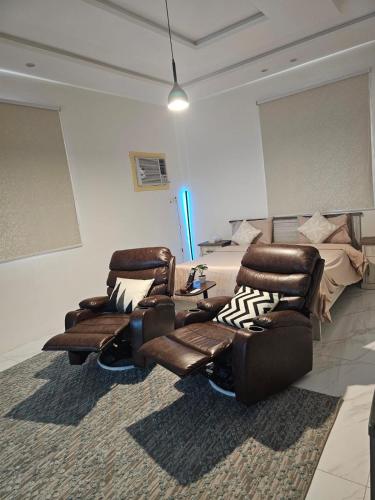 a living room with leather chairs and a bed at شقق جاذر ان السلمانية in As Sayl aş Şaghīr