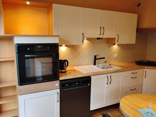 une cuisine avec des armoires blanches et un lave-vaisselle noir dans l'établissement Résidence Frontière Basel Airport, à Saint-Louis