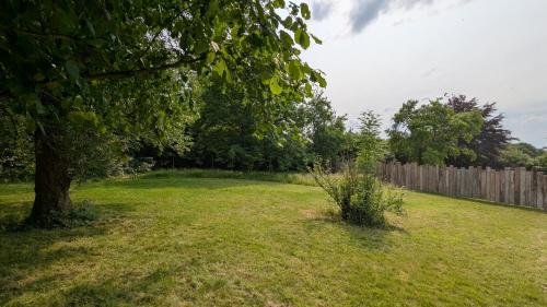 a yard with a tree and a fence at Gîte Ferme de la Chevêche & Jacuzzi Namur in Sart-Saint-Laurent