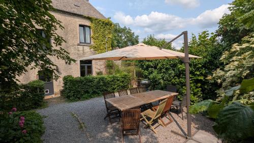 a wooden table with an umbrella in a garden at Gîte Ferme de la Chevêche & Jacuzzi Namur in Sart-Saint-Laurent