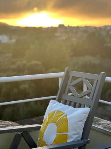 a chair with a pillow on a balcony with the sunset at Coastal Breeze Villa in Sesimbra in Sesimbra
