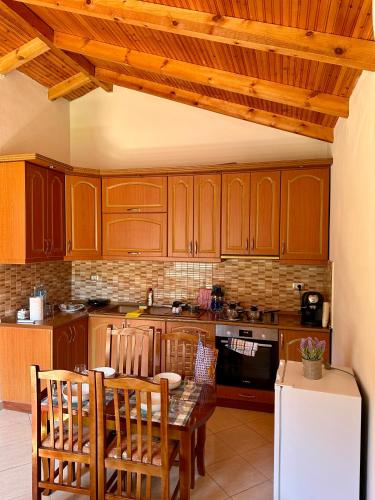 a kitchen with wooden cabinets and a table and chairs at Magnus Apartments in Dukat