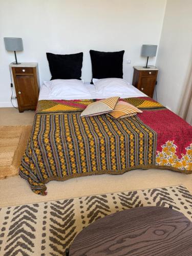 - un lit avec une couverture colorée et 2 tables de chevet dans l'établissement Maison Antibes, à Antibes
