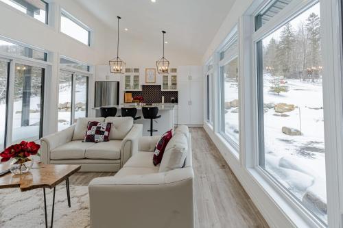 a living room with white furniture and large windows at Mountain Escape with Pool, Near Ski Slopes & Trails in Wentworth-Nord