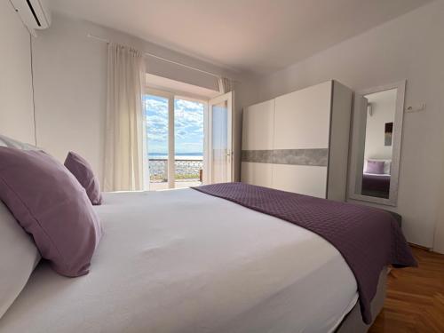 a bedroom with a large white bed with a window at Holiday house Belavista in Novi Vinodolski