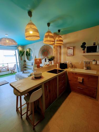a kitchen with a sink and a table with a counter at Les Spas de la Mer, Appart&Spa Aloha, 100m de la plage, Plein cœur du Grau in Le Grau-du-Roi