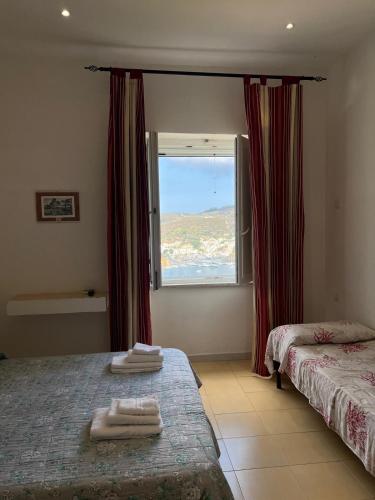 a bedroom with two beds and a window with red curtains at Villa Adele Ponza in Ponza
