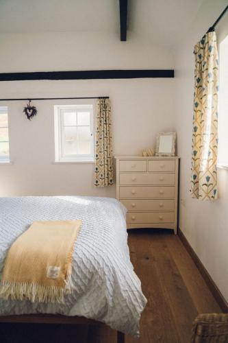 a bedroom with a bed and a dresser and a window at Cosy Underfloor Heated 17th Century Renovated Mill with Stunning Views - Ty Felin in Beddgelert