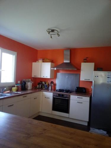 - une cuisine avec des placards blancs et un mur orange dans l'établissement Lepin House, à Lazer