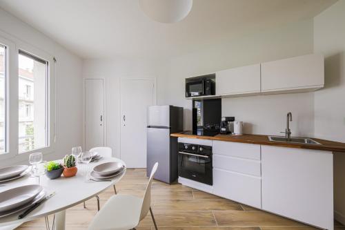 une cuisine avec des armoires blanches et une table avec des chaises dans l'établissement T2 rénové hyper centre vue dégagée, à Grenoble