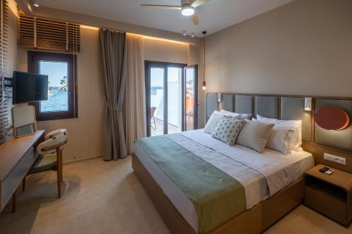 a bedroom with a bed and a desk and a television at Parga Harbor Suites in Parga