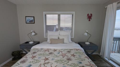 a bedroom with a bed with two lamps and a window at Bay Front Home - Watch the sun rise over LBI. Pier for Boat/Swim/SUP/Kayak/Crab in Manahawkin